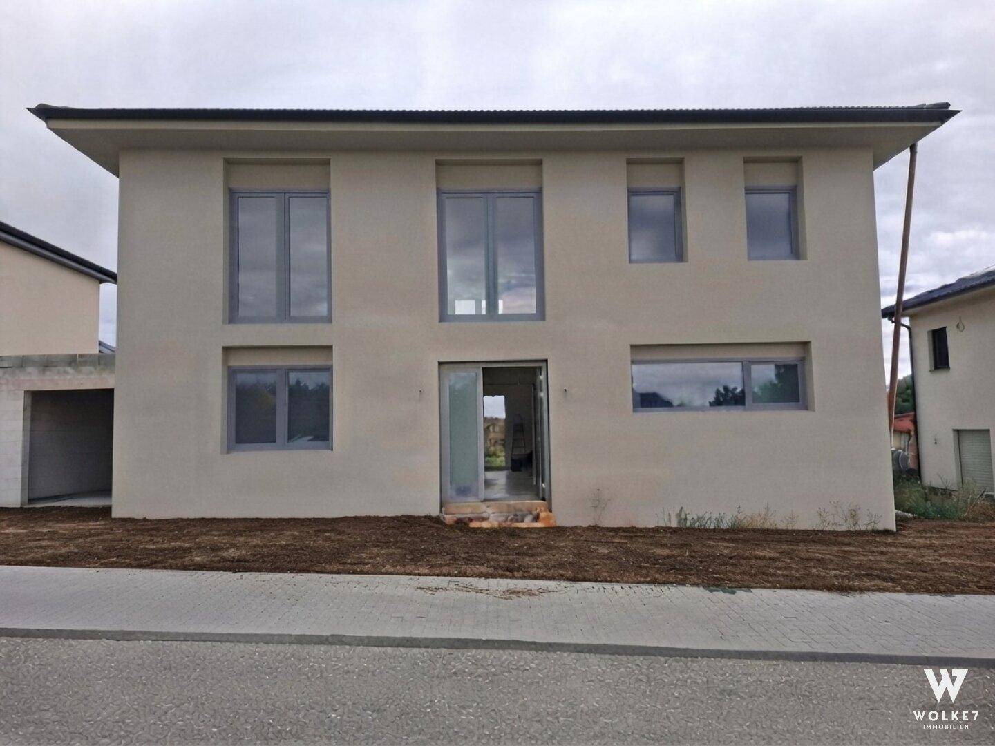 Rückansicht des Neubaus im Rohzustand mit unfertigem Außenbereich.