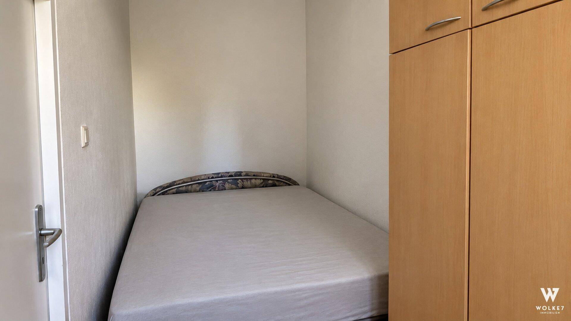 Kleines Schlafzimmer mit Einzelbett und integriertem Kleiderschrank, ideal als Gästezimmer.