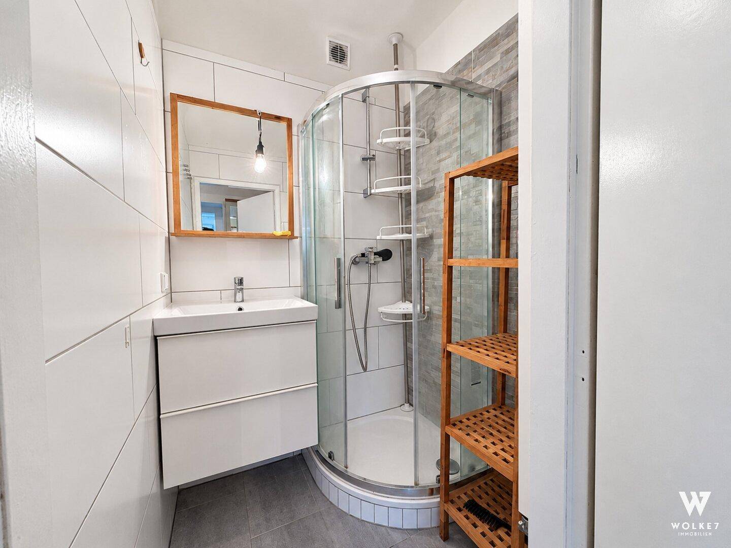 Modernes Badezimmer mit weiß gefliesten Wänden, einer Eckdusche und einem Waschbecken mit Unterschrank.