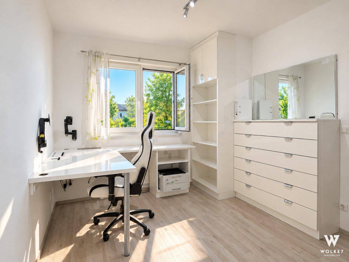 Helles Arbeitszimmer mit Schreibtisch, Bürostuhl und Blick ins Grüne durch das Fenster.