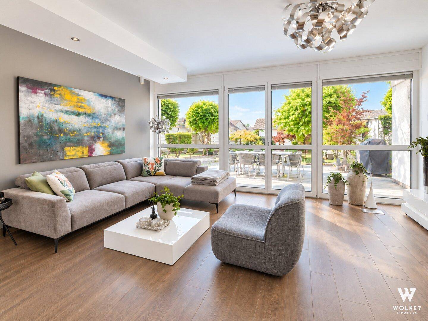 Geräumiges Wohnzimmer mit großen Fenstern, Holzboden und moderner Einrichtung.