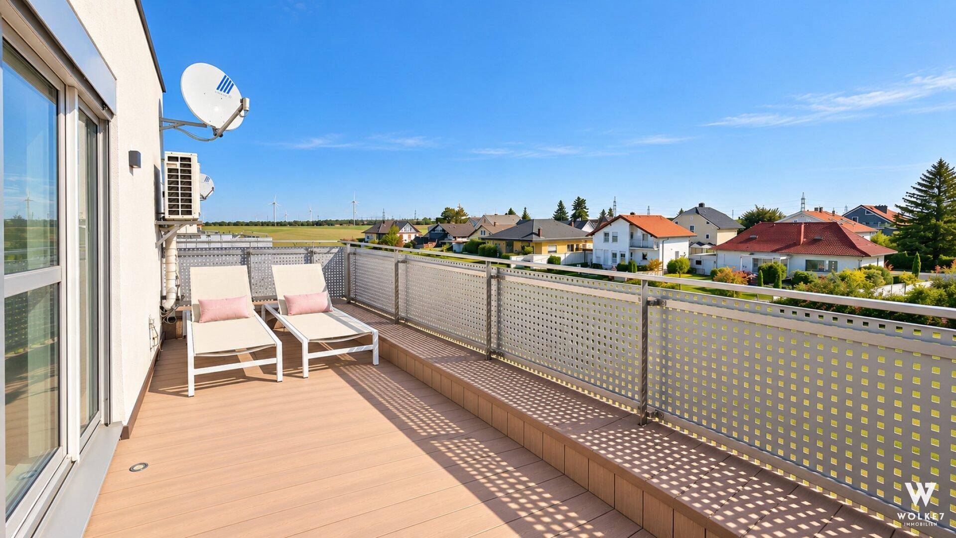Lange Terrasse mit Sonnenliegen und weitem Blick über die ländliche Umgebung.