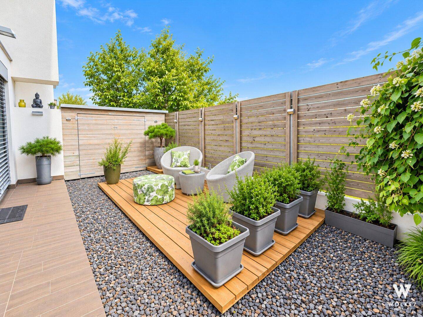 Kleiner, gemütlicher Gartenbereich mit Holzdeck, Sitzgelegenheiten und Gartenhaus.
