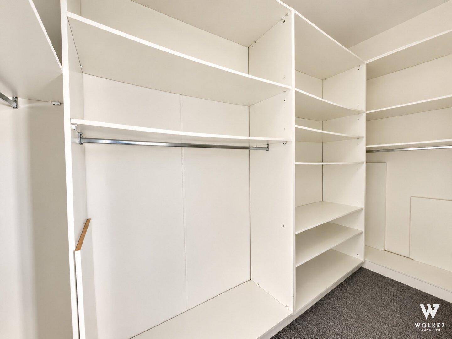 Geräumiger begehbarer Kleiderschrank mit weißen Regalen und Kleiderstangen für viel Stauraum.