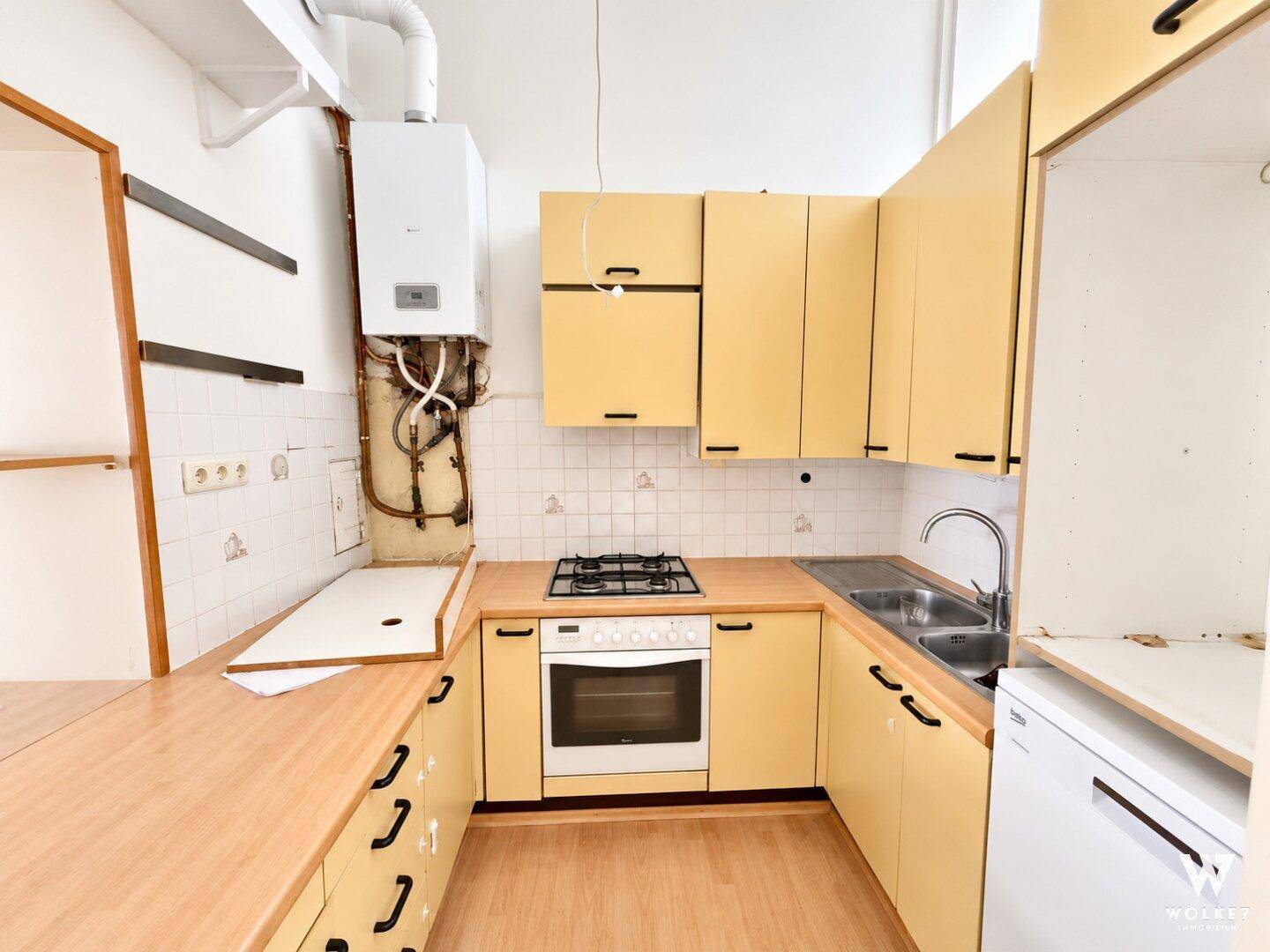 Funktionale Küche mit gelben Schränken, Holz-Arbeitsplatten und Gasherd, bereit zur Nutzung.