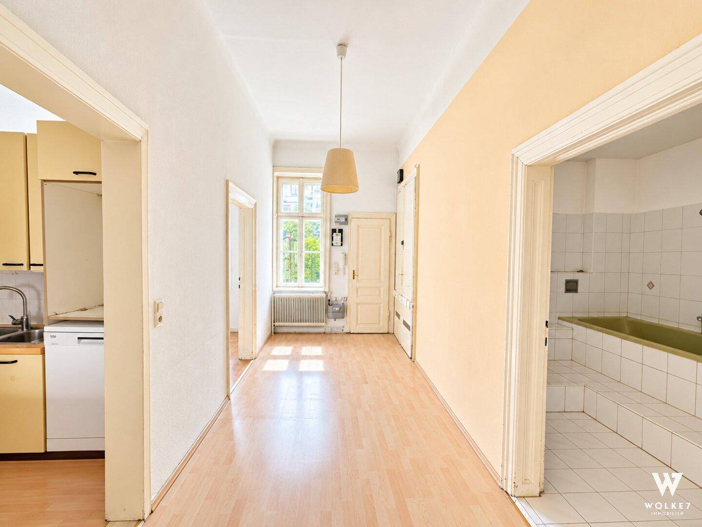 Heller Flur mit Laminatboden, der zu verschiedenen Räumen führt, darunter Küche und Bad.
