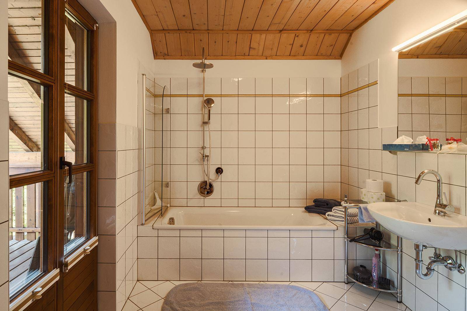 Helles Badezimmer mit Badewanne, Duschbereich und Fenster, klassisch gefliest.
