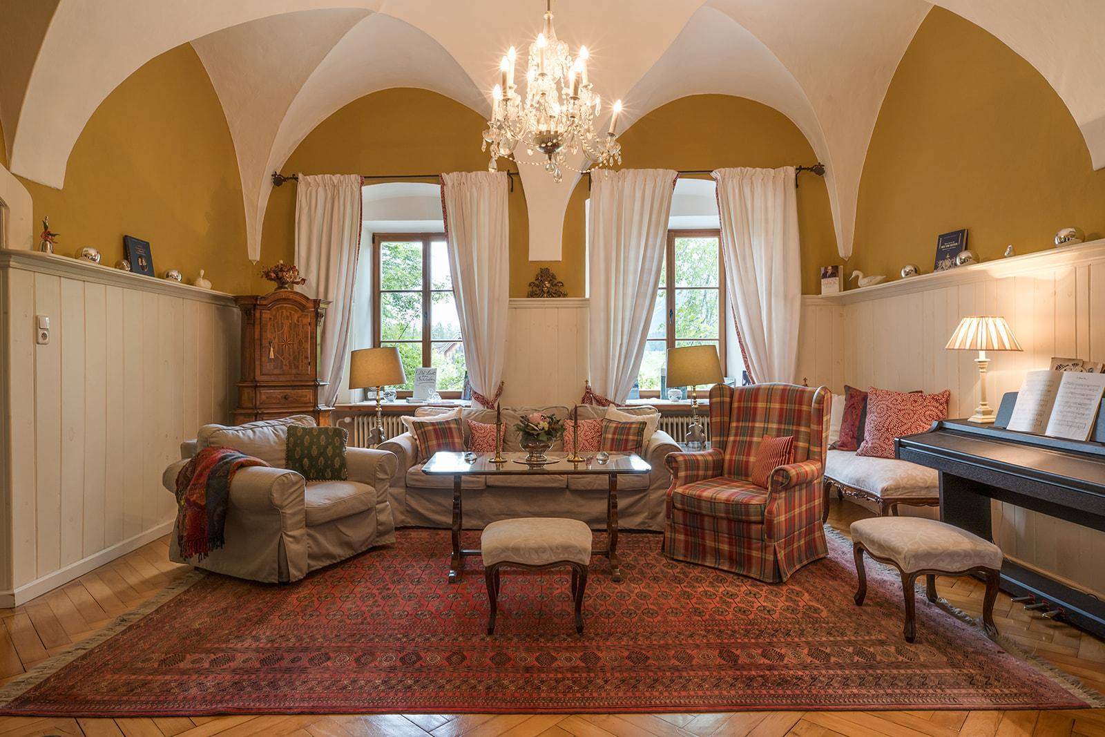 Helles Wohnzimmer mit Gewölbedecke, traditionellen Möbeln und einem Klavier für musikalische Abende.