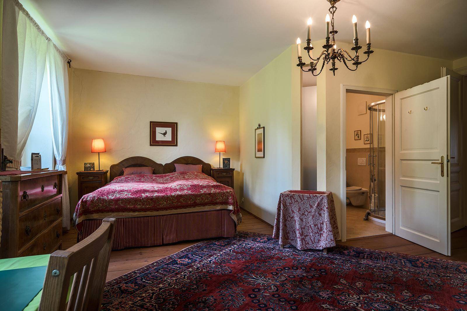 Komfortables Schlafzimmer mit traditionellem Teppich, Holzboden und direktem Zugang zum Badezimmer.