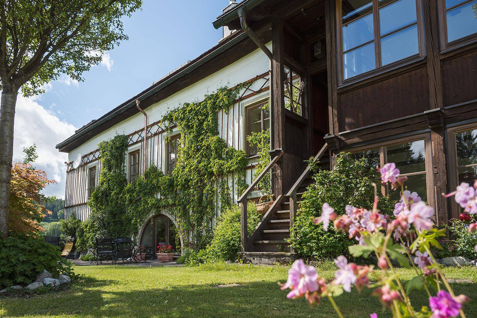 Historisches Gebäude mit charmanten Holzdetails, begrünten Fassaden und Zugang zum Gartenbereich.