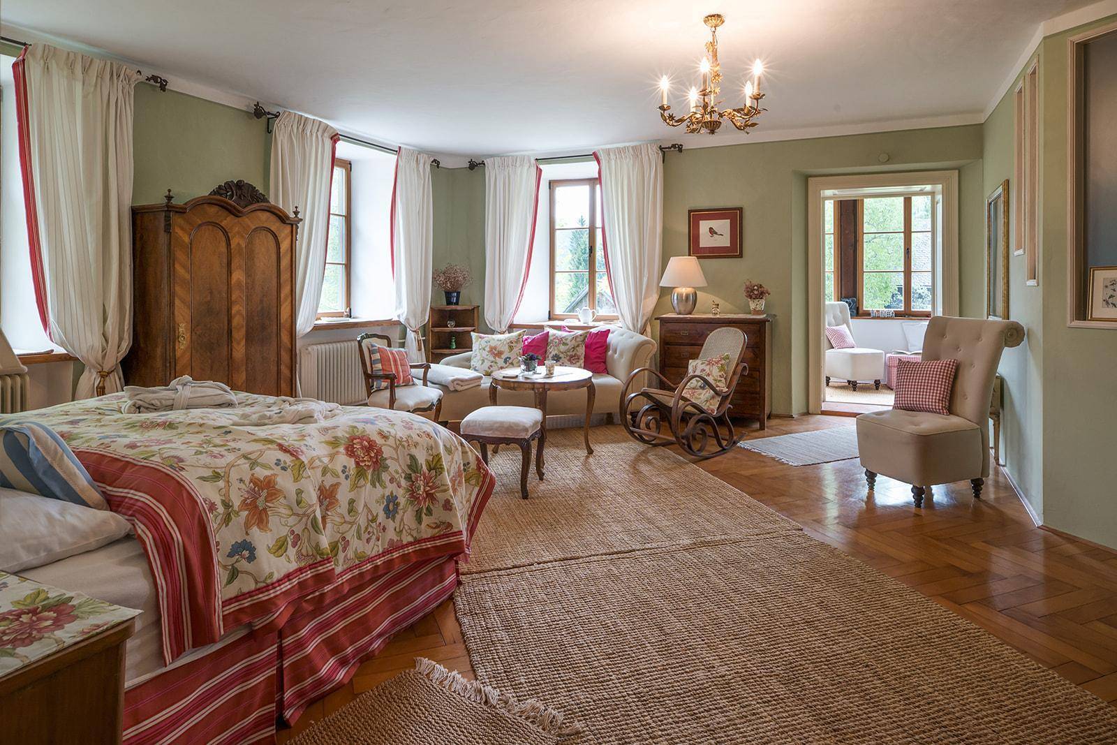 Großzügiges Schlafzimmer mit traditionellem Interieur, Holzboden und Zugang zu einem weiteren Raum.