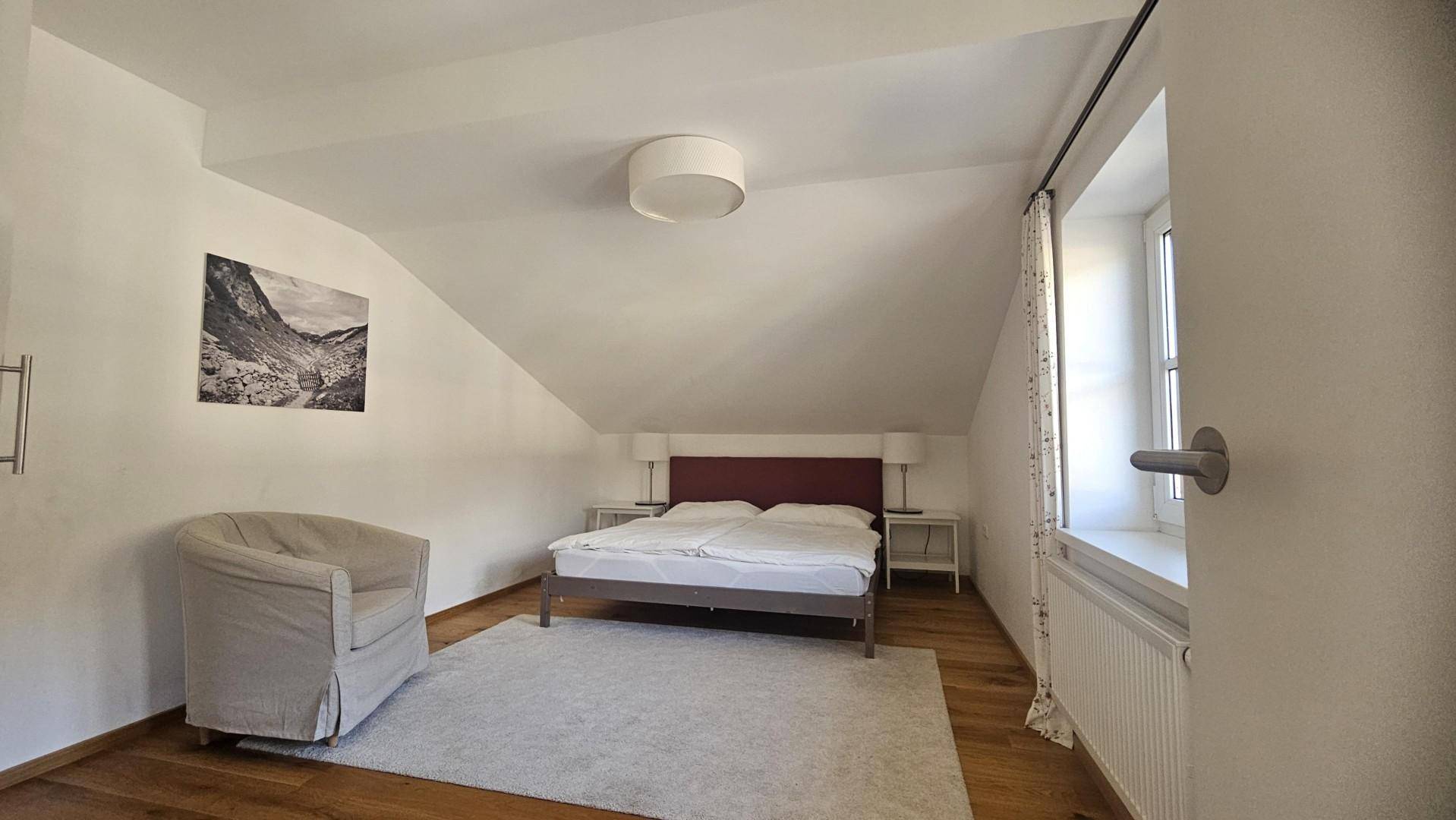 Gemütliches Schlafzimmer im Dachgeschoss mit Holzboden und schrägen Wänden.