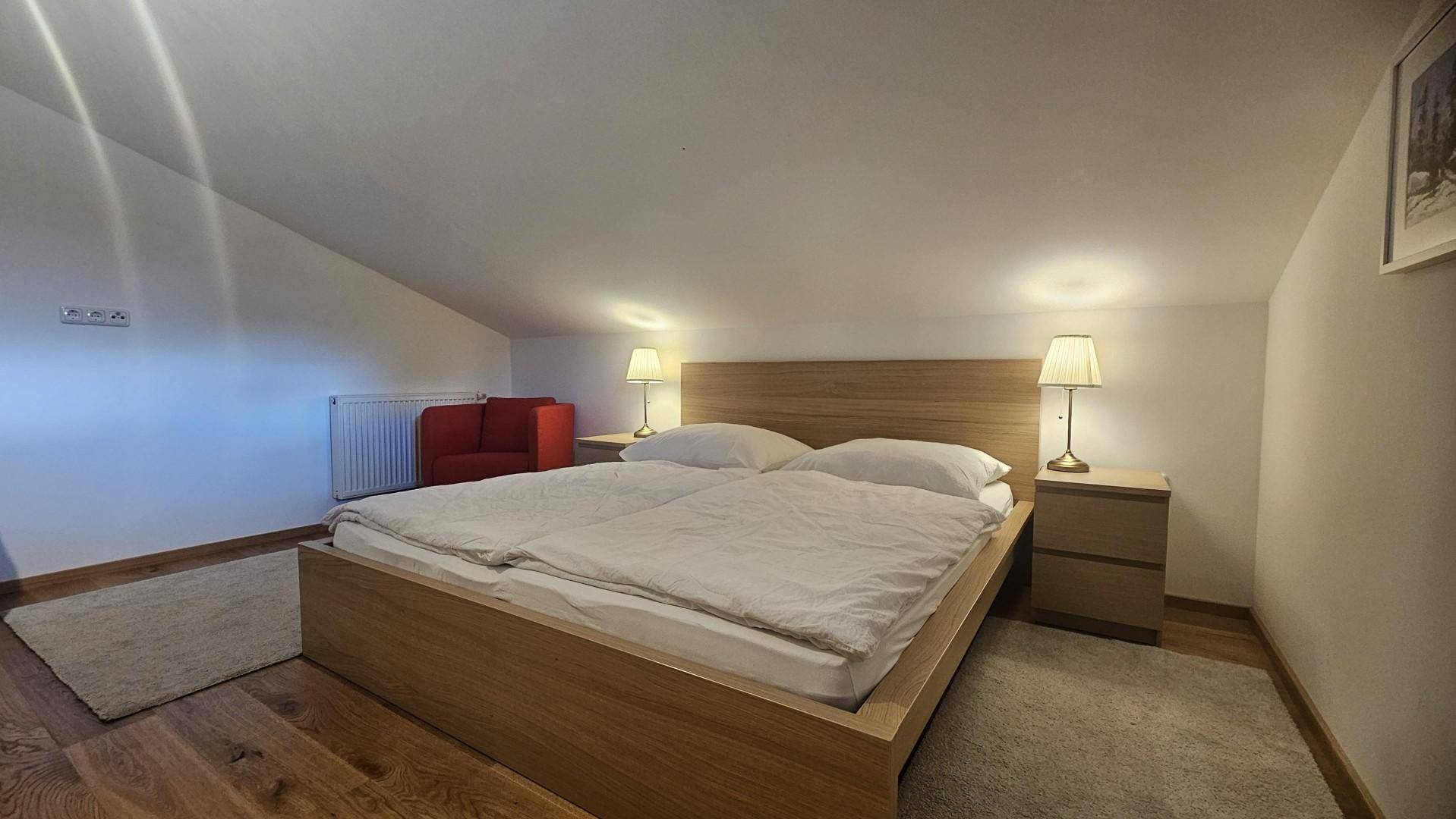 Helles Schlafzimmer mit Doppelbett, Holzboden und Nachttischen im Dachgeschoss.