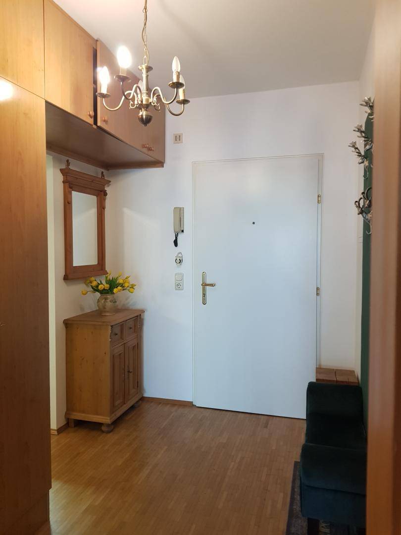 Heller Eingangsbereich mit Holzboden, Einbauschränken und einer Garderobe.