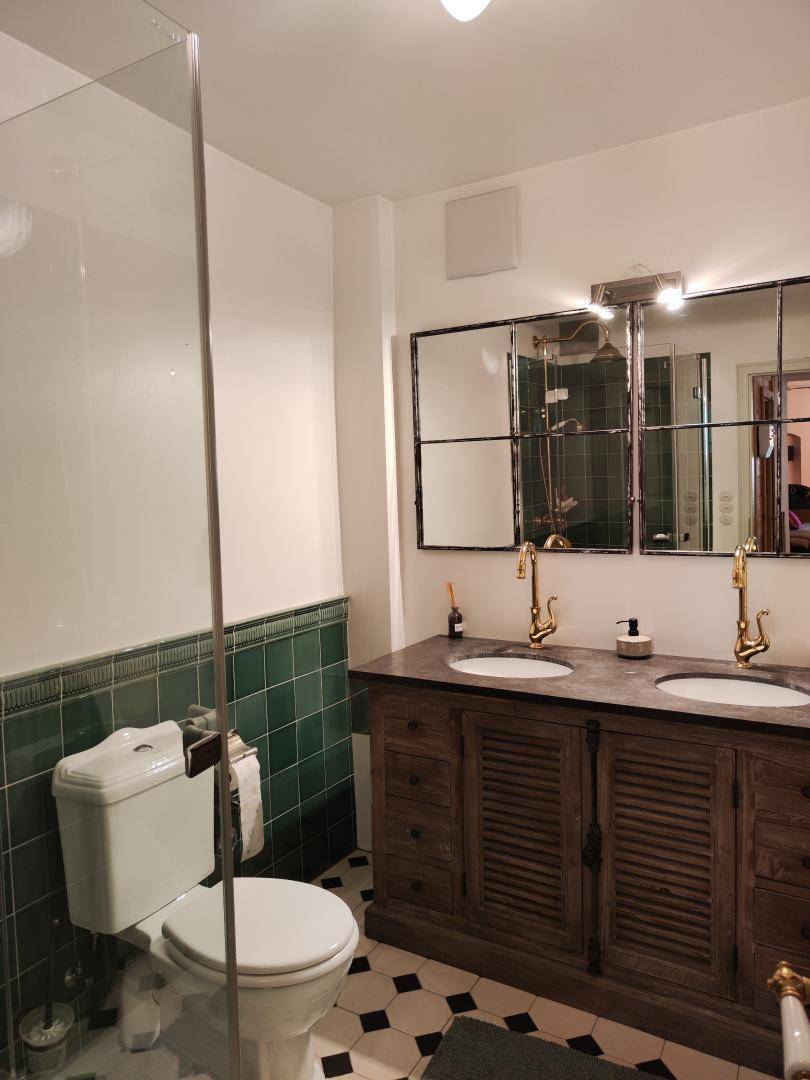 Elegantes Badezimmer mit Doppelwaschbecken, grünen Fliesen und modernen Armaturen.
