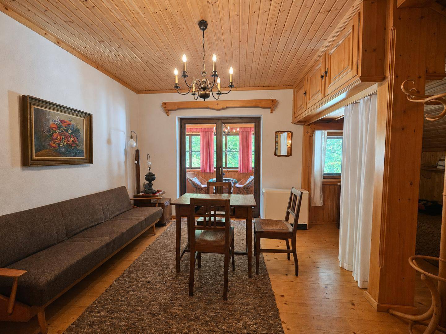 Gemütliches Wohnzimmer im alpinen Stil mit Holzboden, Holzdecke und traditionellen Möbeln.
