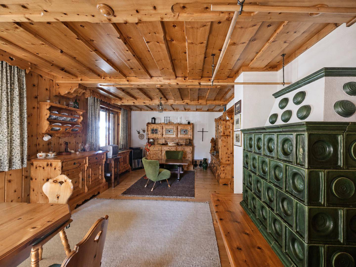 Geräumiges Wohnzimmer mit traditionellem Kachelofen, Holzwänden und rustikalen Möbeln.