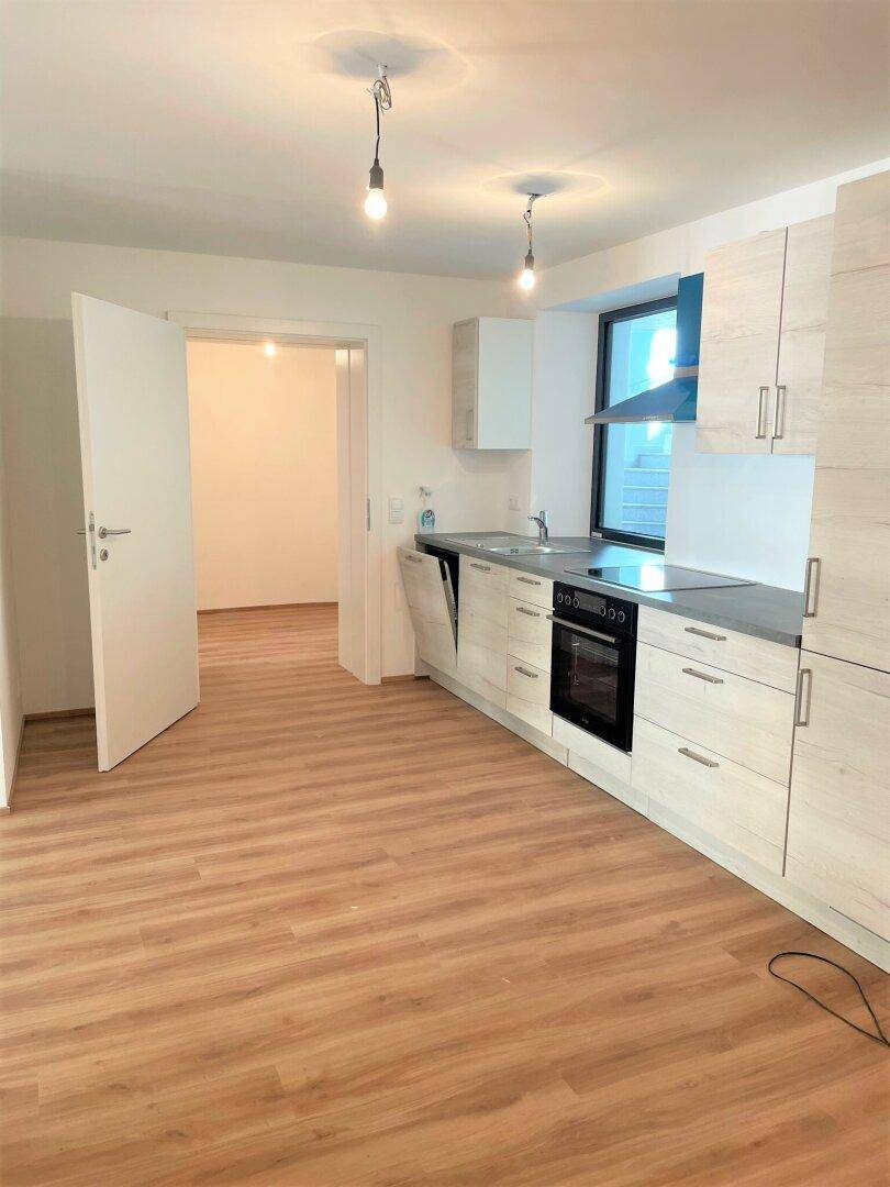 Helle Einbauküche mit modernen Holzfronten, integrierten Geräten und Blick in den Flur.