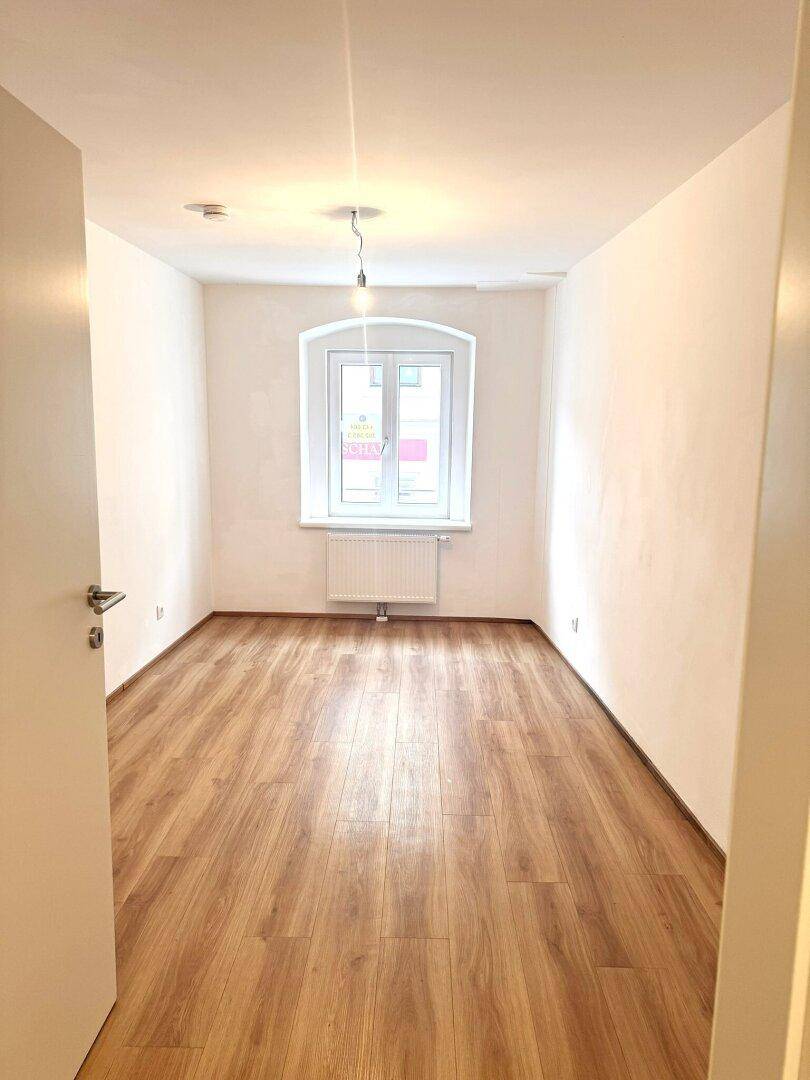 Schmaler, heller Raum mit Laminatboden und einem Fenster, ideal als Schlaf- oder Arbeitszimmer.