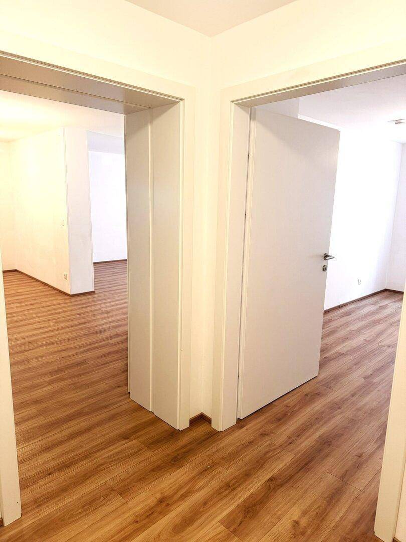 Heller Flur mit Laminatboden und mehreren Türen, die zu den verschiedenen Räumen führen.