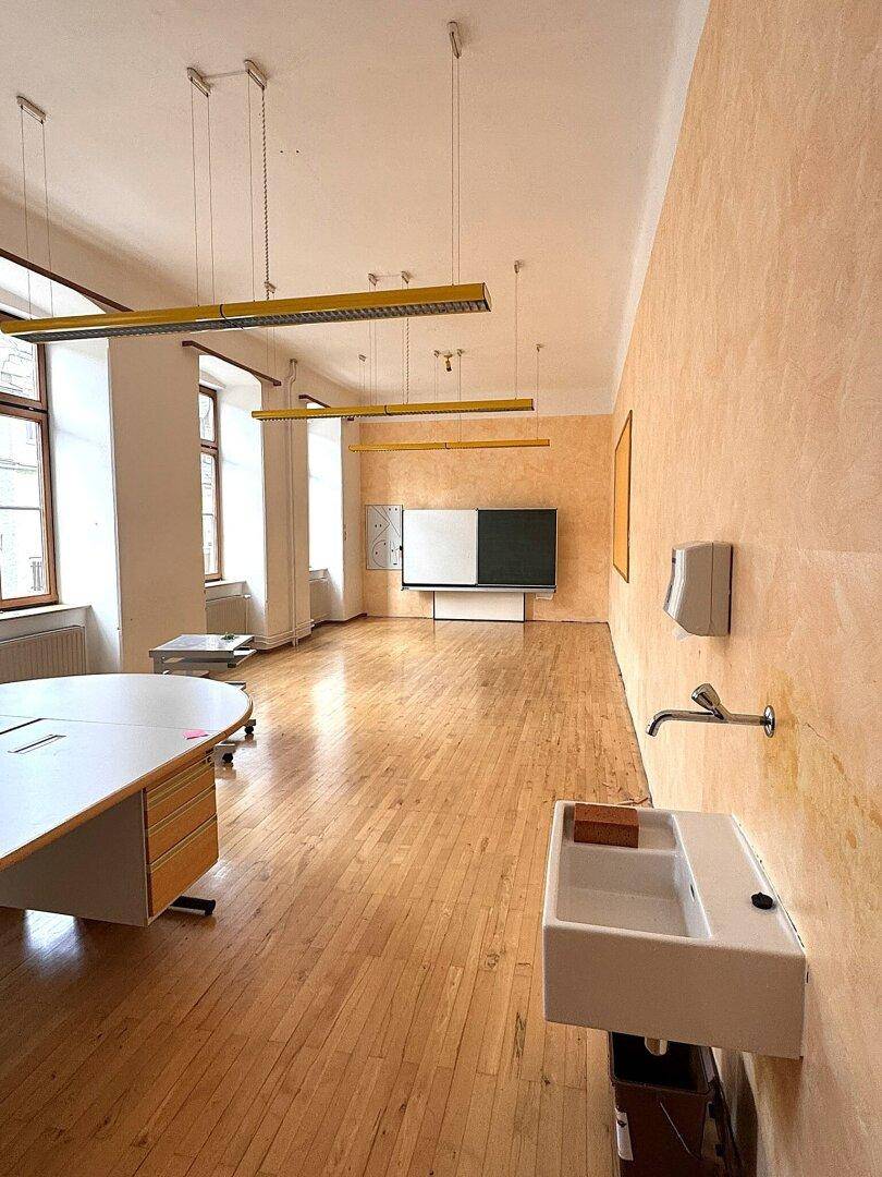 Großer Raum mit Parkettboden, Schreibtisch und Waschbecken, ideal für kreative Arbeitsbereiche.