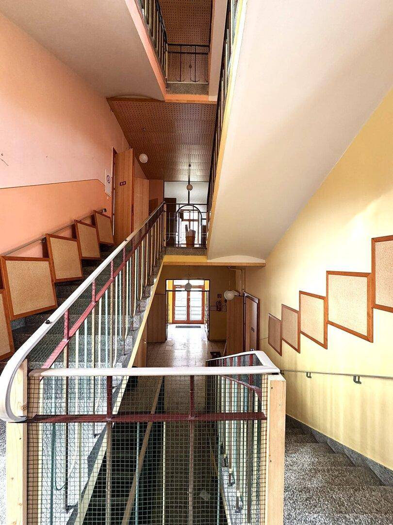 Geräumiges Treppenhaus mit mehreren Etagen, Terrazzoboden und natürlichem Lichteinfall.