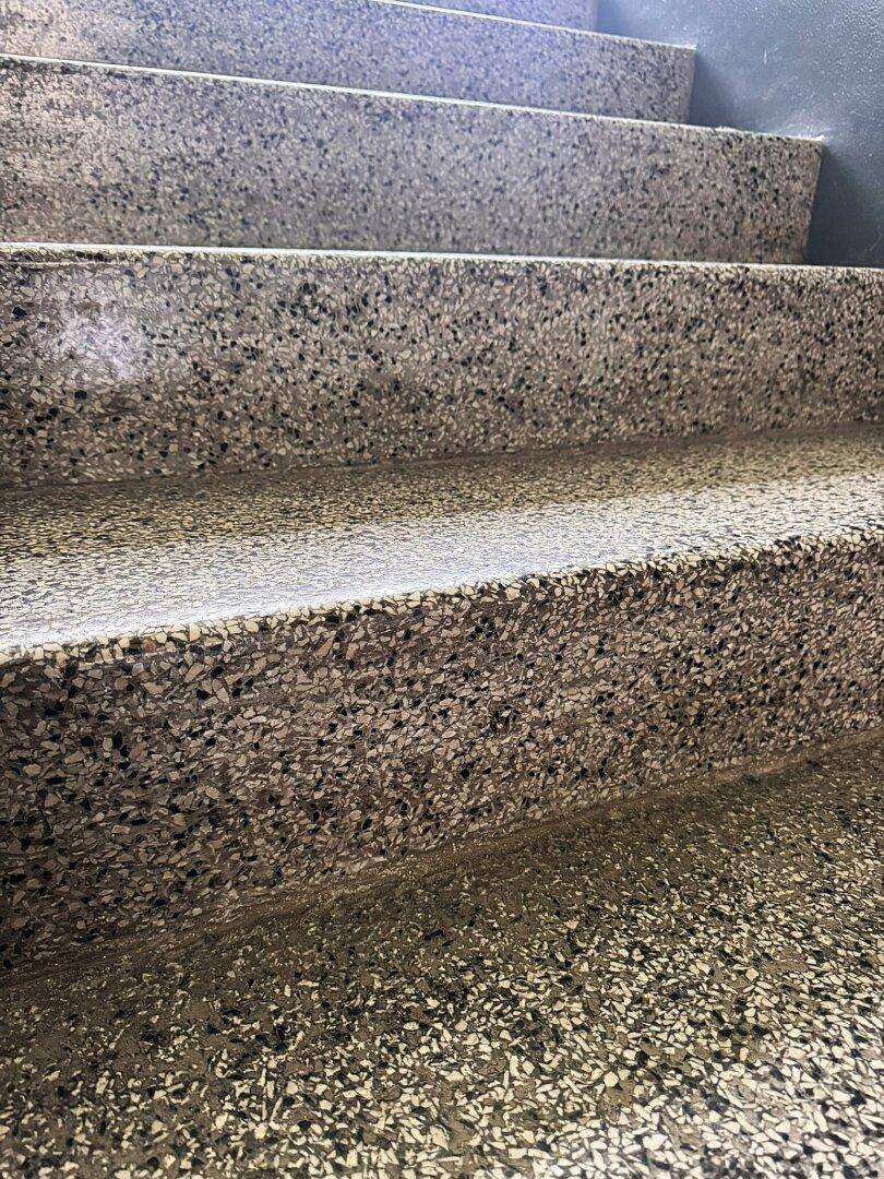 Nahaufnahme von Terrazzostufen mit feiner Körnung und dunklen Einschlüssen.