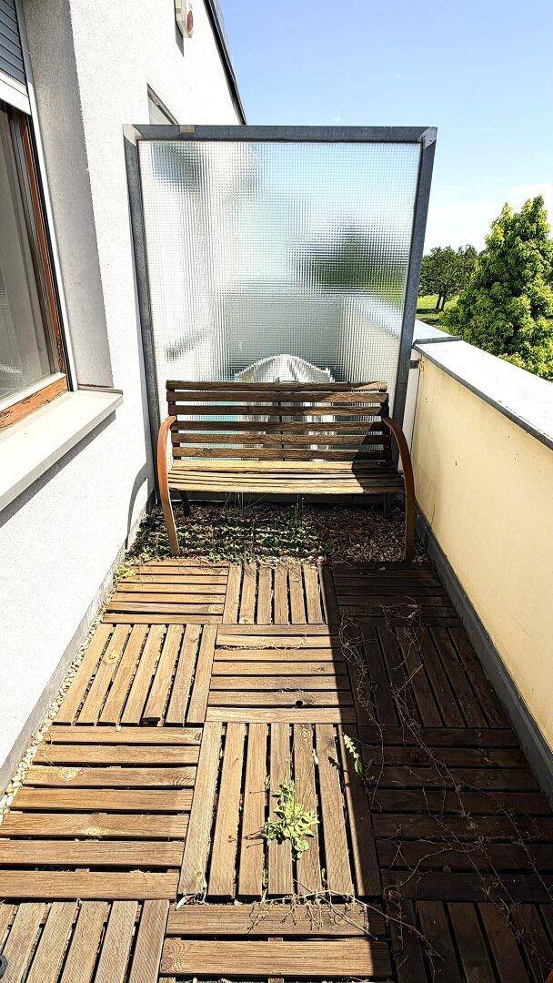 Balkon mit Holzdielen und einer Holzbank, bereit für eine Neugestaltung des Außenbereichs.