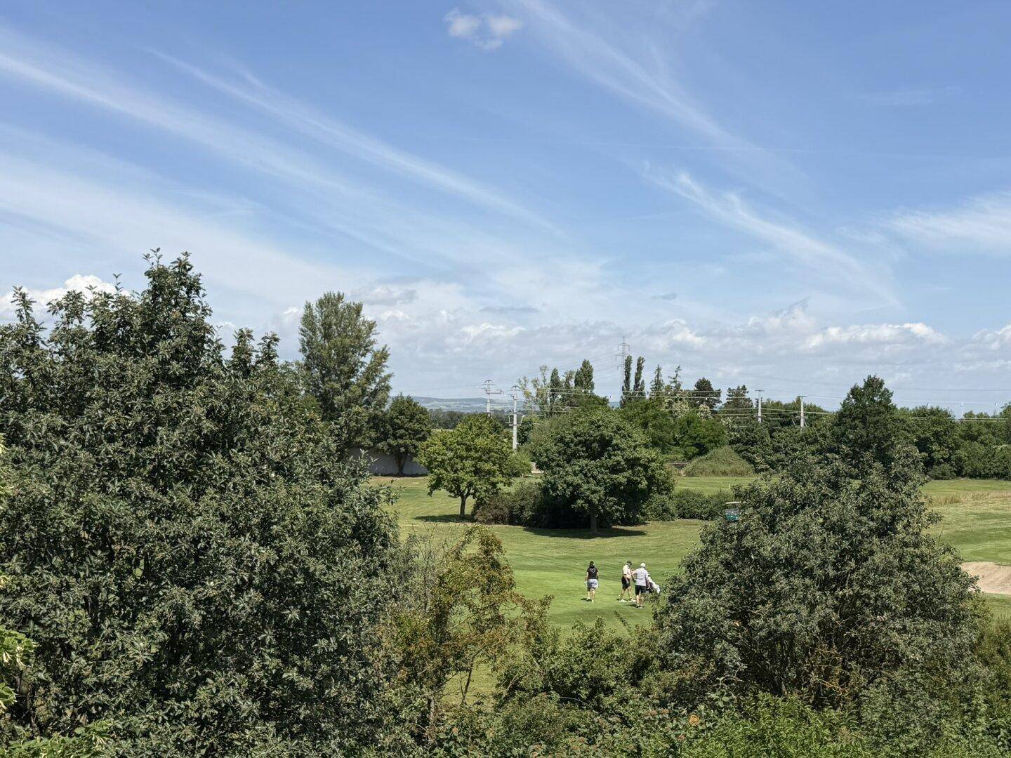Panoramablick auf einen weitläufigen Golfplatz mit grünen Fairways und spielenden Golfern.