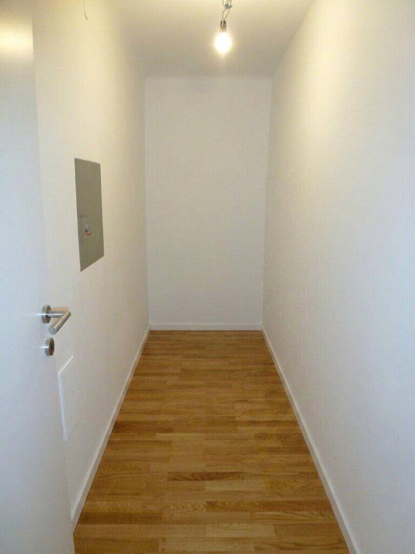 Leerer, schmaler Raum mit hellem Parkettboden, ideal als Abstellraum nutzbar.