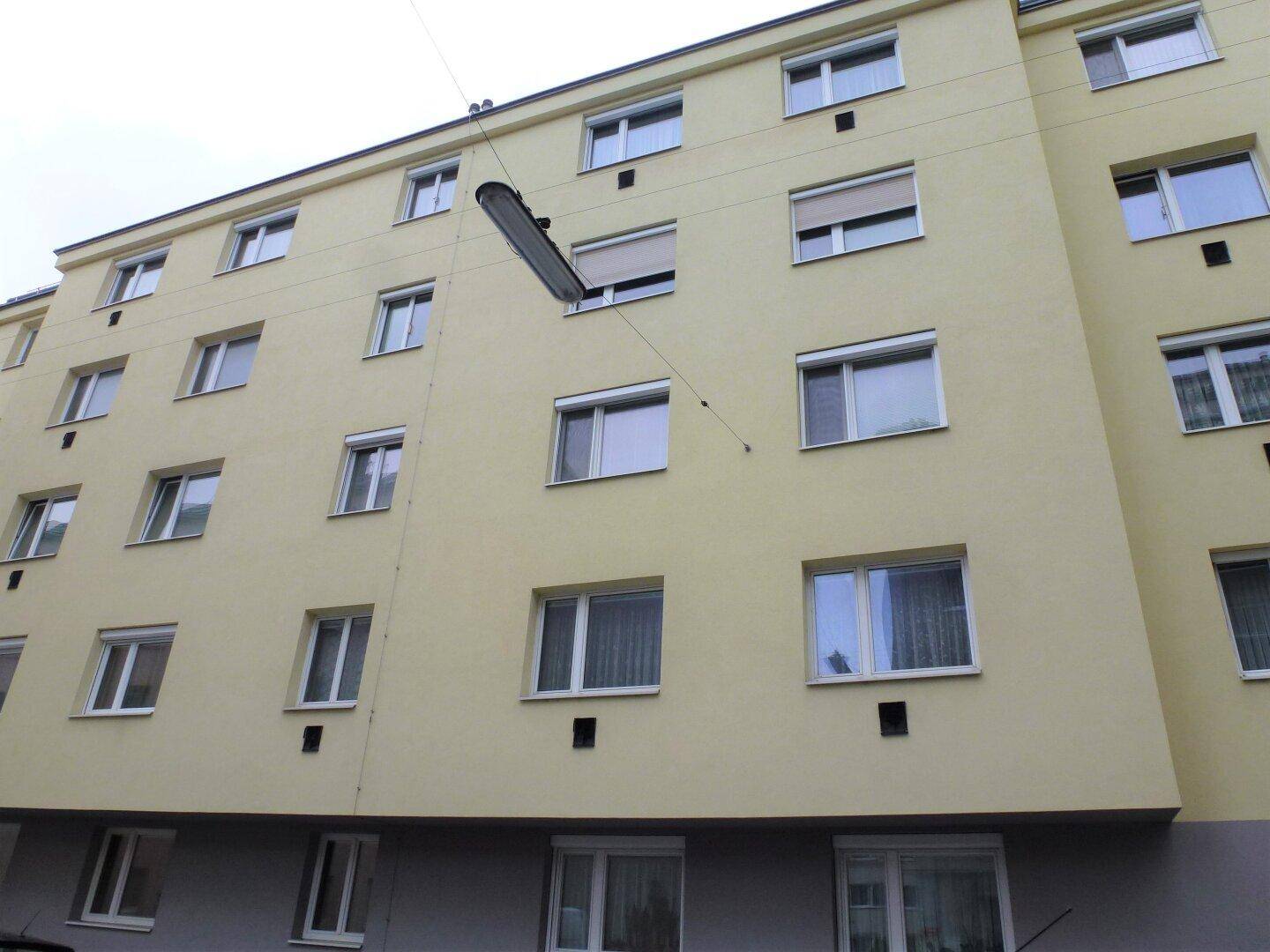 Fassade eines mehrstöckigen Wohngebäudes mit zahlreichen Fenstern und heller Farbgebung.