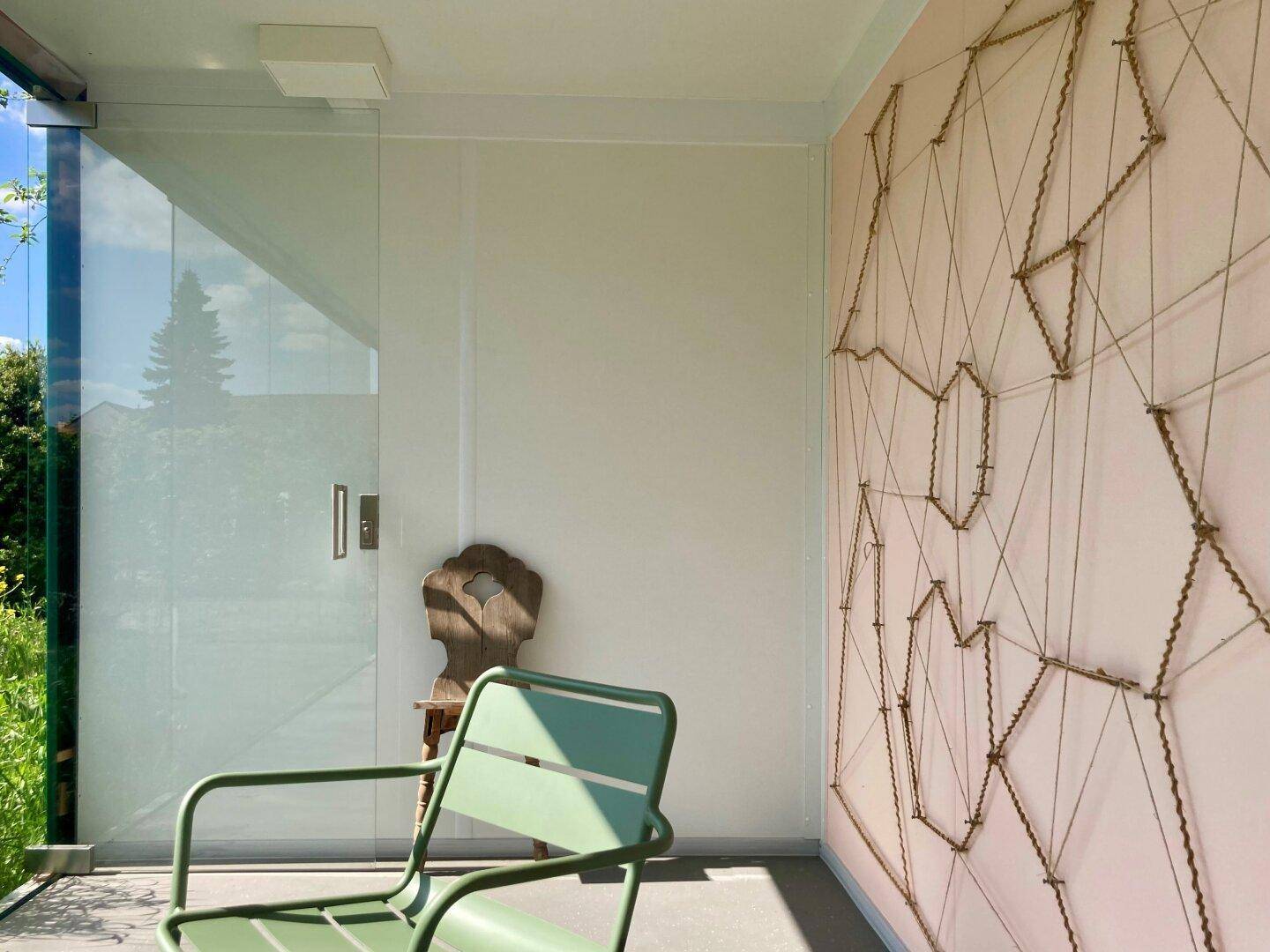 Überdachte Loggia mit Glaswänden und einer dekorativen Wandgestaltung, ideal zum Entspannen.