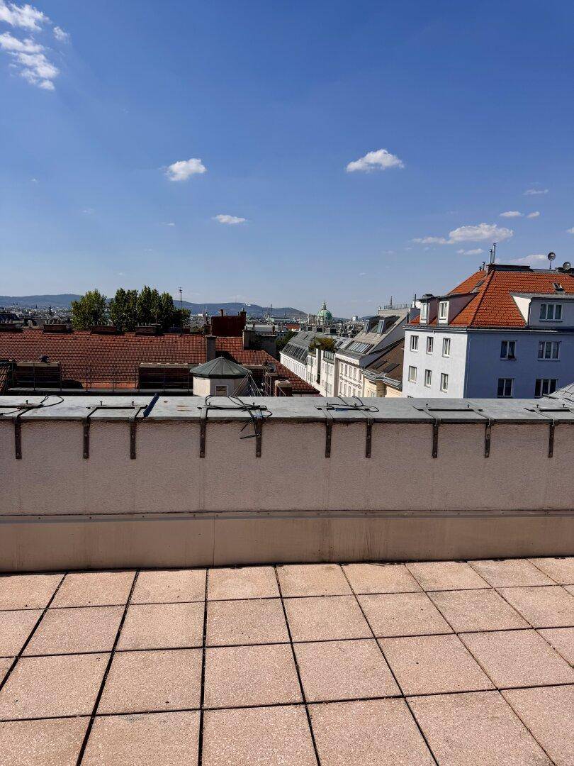 Weitläufige Dachterrasse mit Panoramablick über die historische Stadtkulisse unter strahlend blauem Himmel.