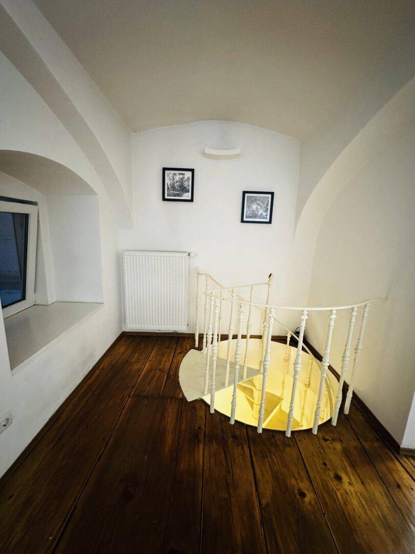 Heller Flur mit einer eleganten Wendeltreppe und einem Heizkörper an der Wand.
