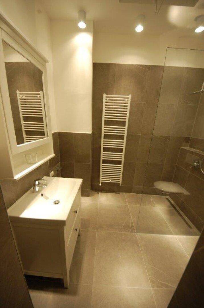 Modernes Badezimmer mit Einzelwaschbecken, beheiztem Handtuchhalter und Duschbereich.