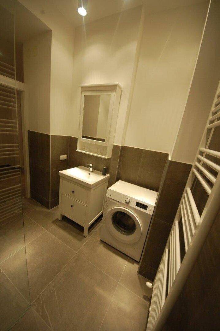 Badezimmer mit Waschmaschine, Einzelwaschbecken und beheiztem Handtuchhalter.