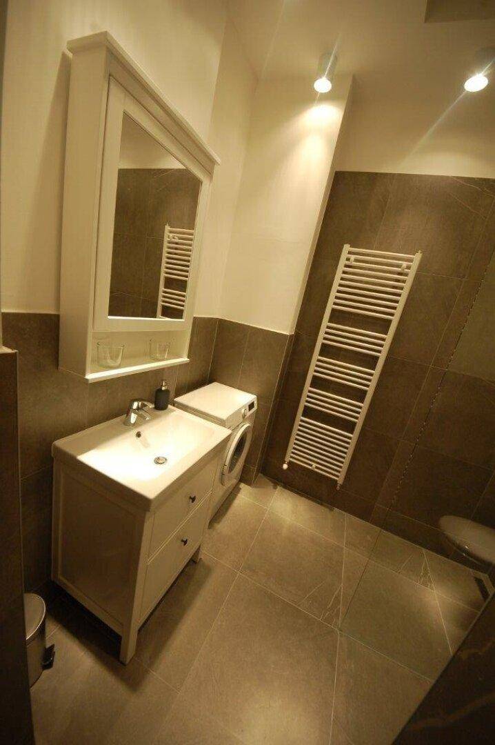 Helles Badezimmer mit Waschmaschine, Waschtisch und beheiztem Handtuchtrockner.
