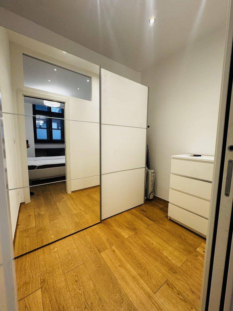 Raum mit großen Spiegelschiebetüren und hellem Holzboden.