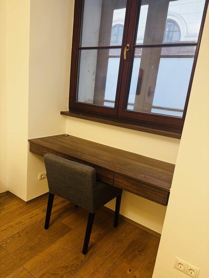 Kleiner Arbeitsbereich mit Holzschreibtisch und Fenster, ideal für Home-Office-Nutzung.