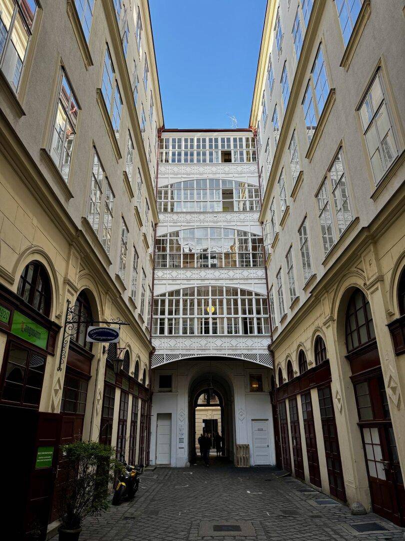 Historischer Innenhof mit vielen Fenstern und einem Durchgang, der zum Gebäude führt.