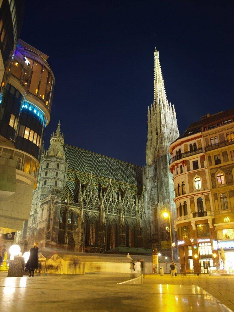 Nachtansicht des Stephansdoms in Wien, umgeben von beleuchteten Stadtgebäuden.