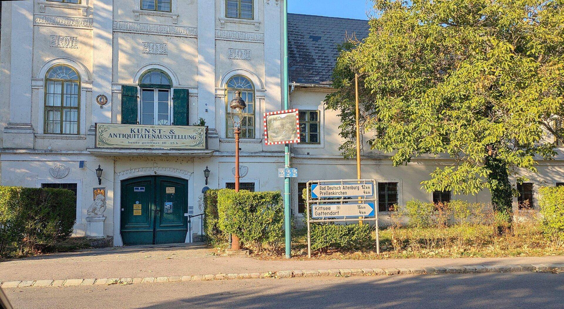 Historische Gebäudefassade mit grünen Fensterläden und einem Eingangsbereich an einer Straße.