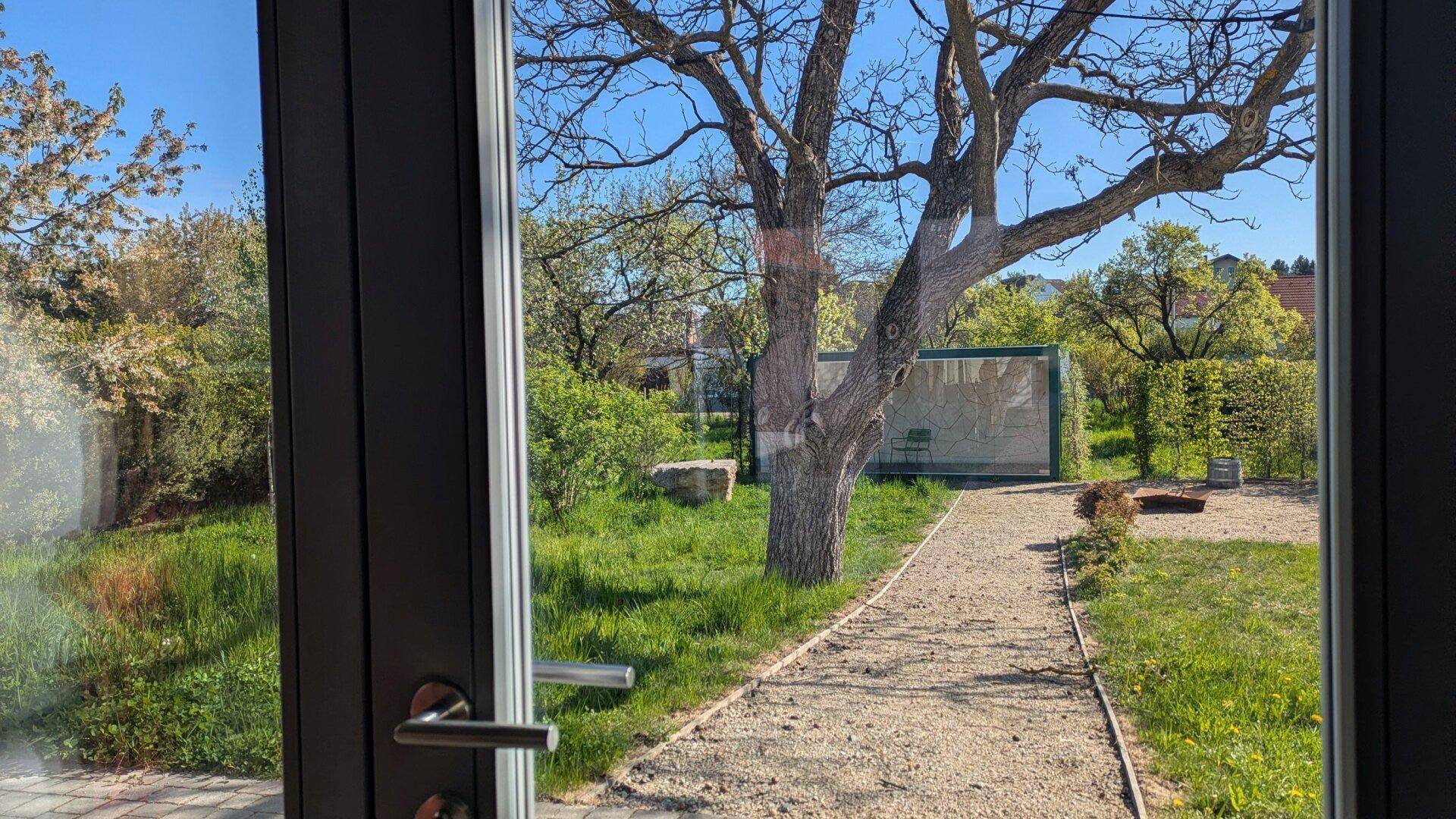 Heller Innenraum mit großen Fenstern, die einen weiten Blick auf den grünen Garten und die Natur bieten.