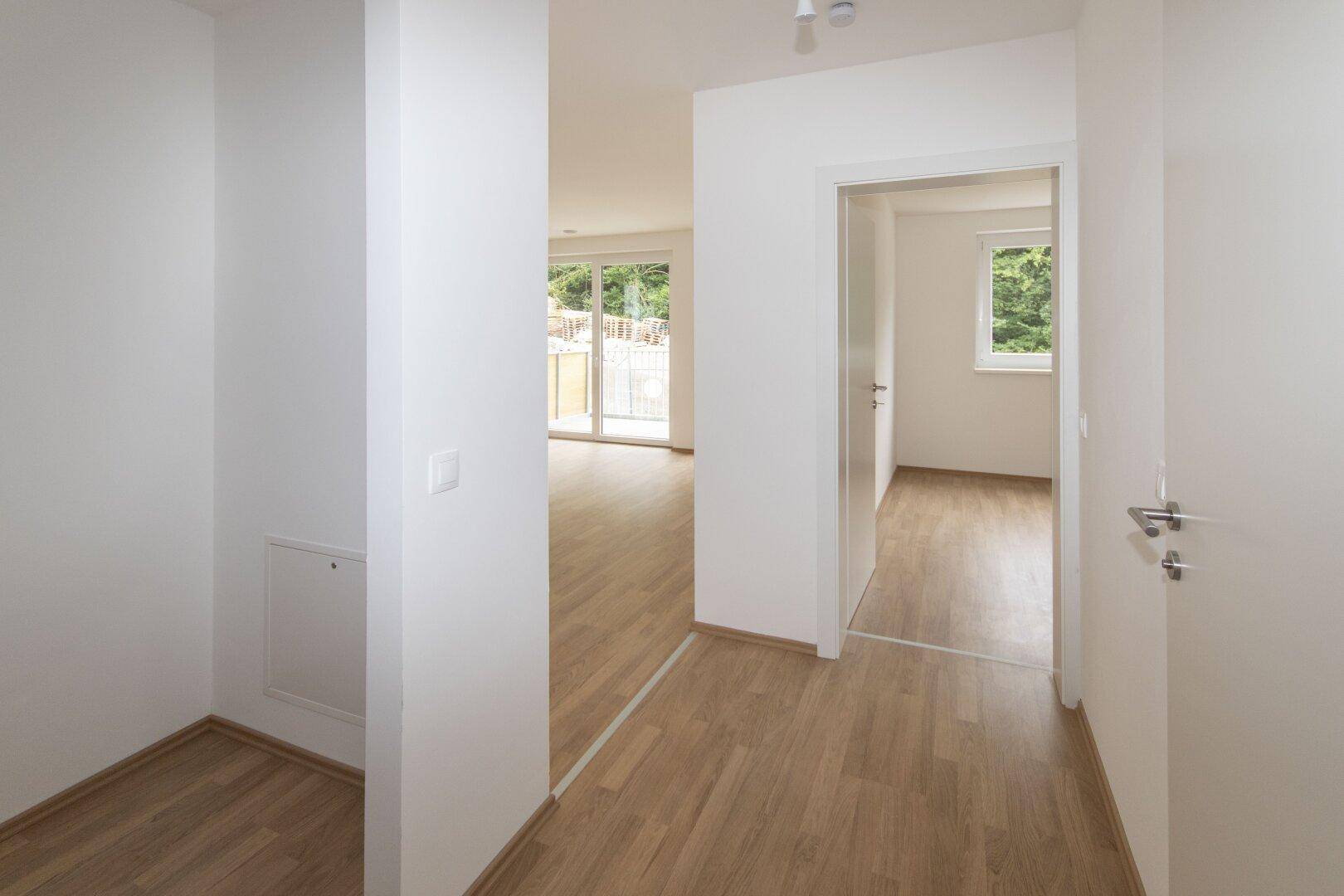 Heller Flur mit hellem Laminatboden und weißen Wänden, der zu den angrenzenden Räumen führt.