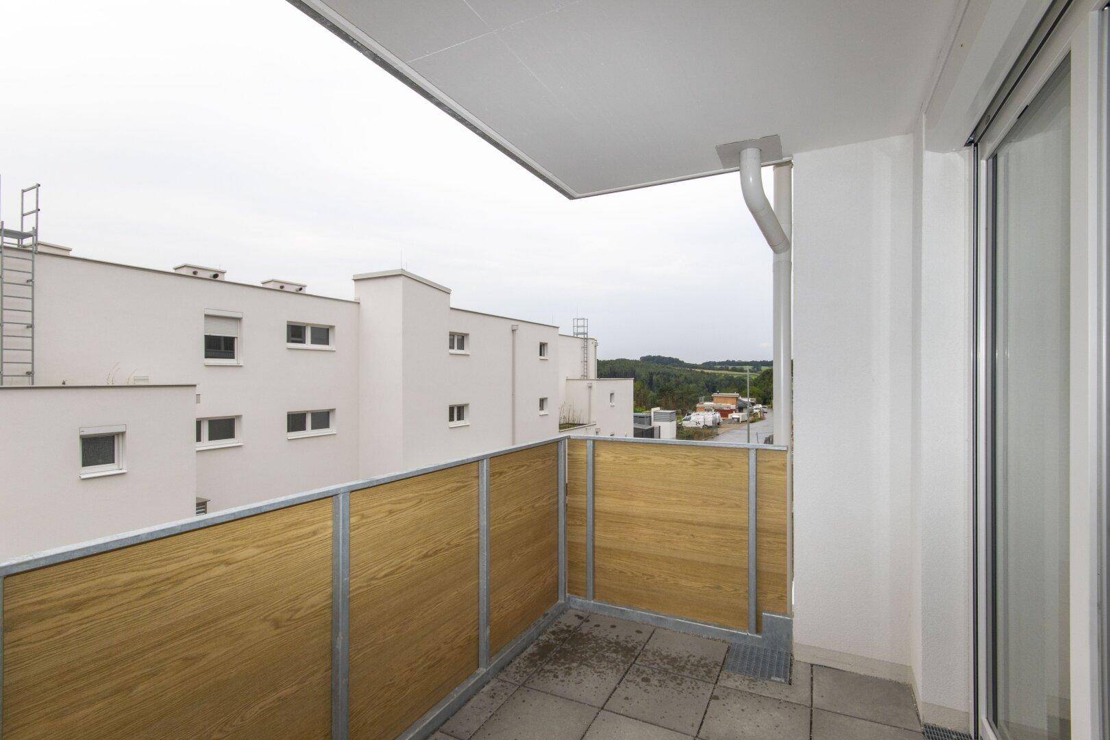 Balkon mit Fliesenboden und Blick auf die umliegenden Gebäude und die Landschaft.