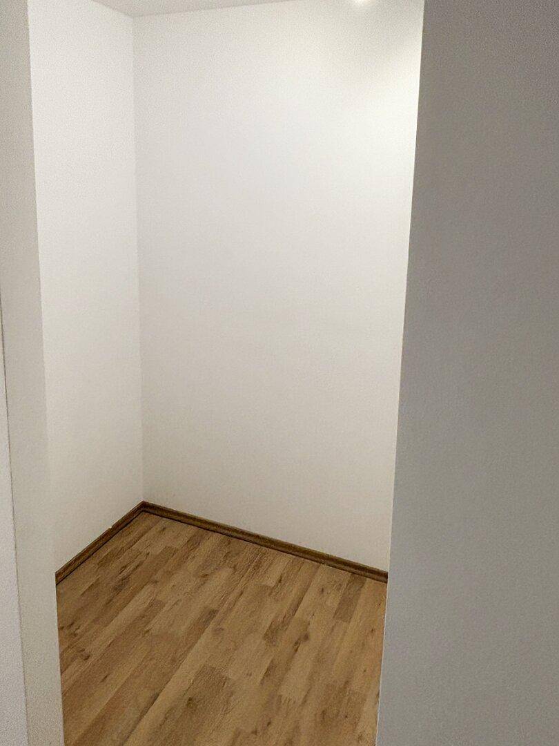 Kleiner, leerer Abstellraum mit Laminatboden und weißen Wänden, ideal für zusätzlichen Stauraum.