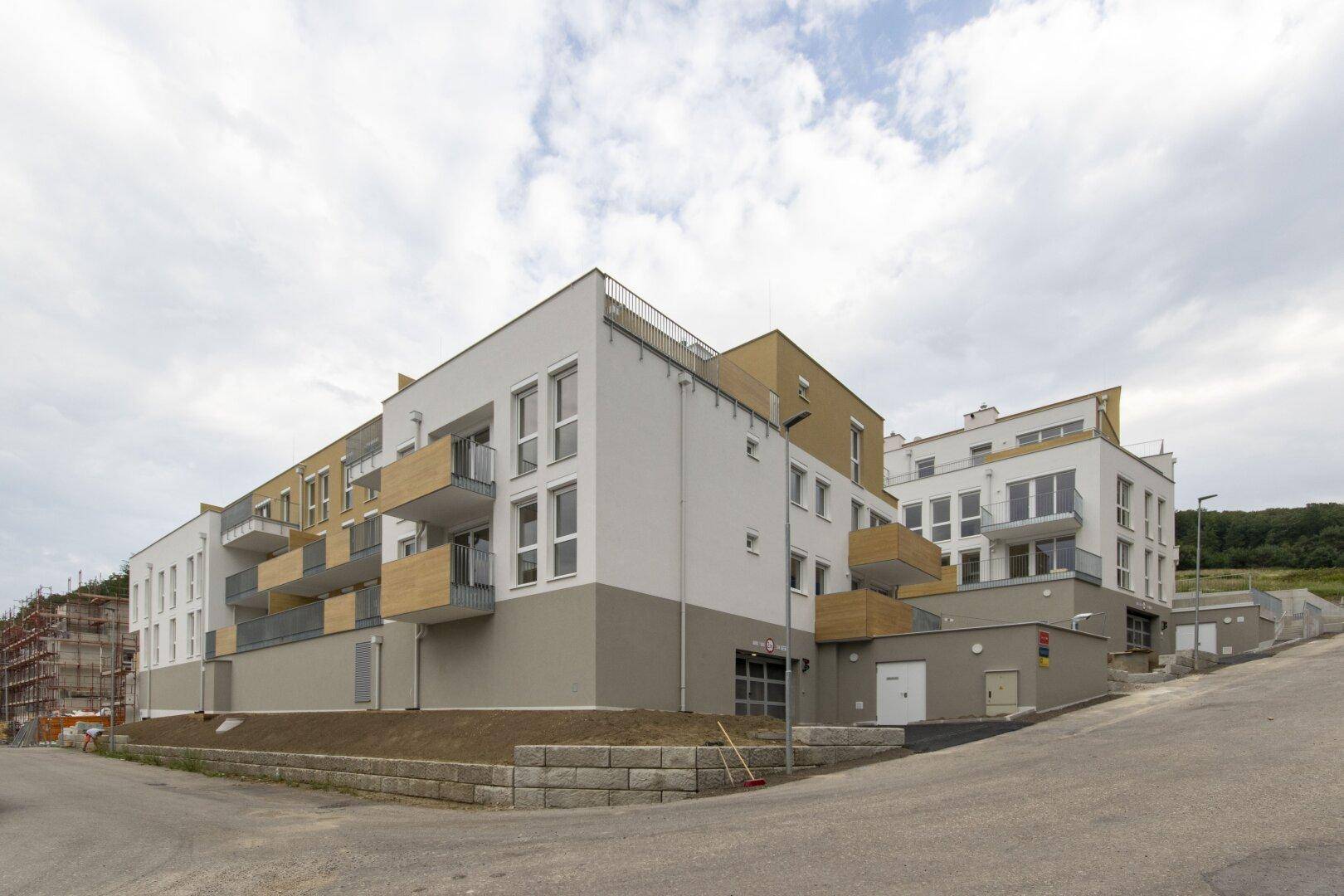 Moderne Wohnanlage am Hang mit gestuften Gebäuden, weißen Fassaden und Balkonen.