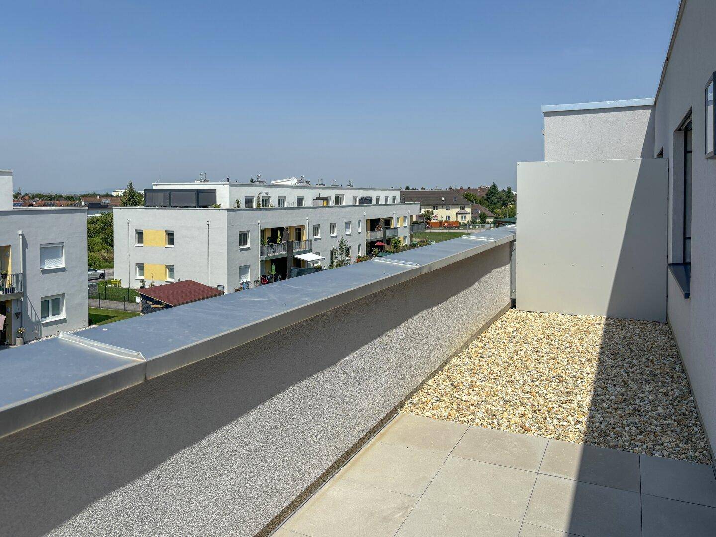 Sonnige Terrasse mit Blick auf die umliegenden Neubauten und die Stadt.