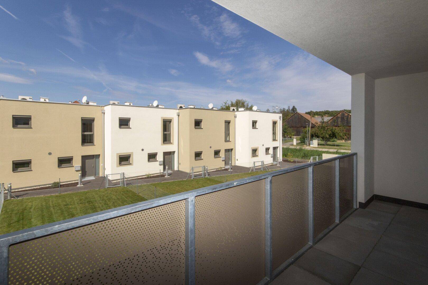 Balkon mit weitem Blick über die gepflegten Rasenflächen und die modernen Reihenhäuser.
