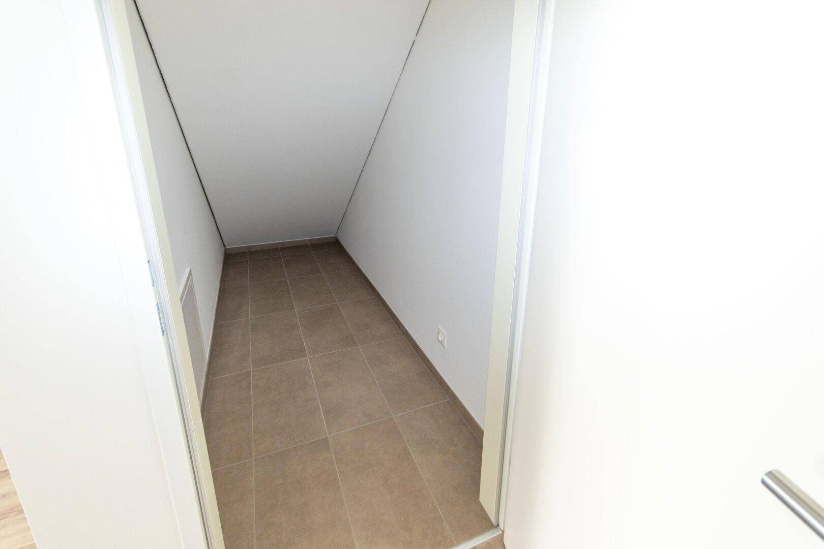 Praktischer Abstellraum mit schräger Decke und Fliesenboden, ideal für zusätzlichen Stauraum.